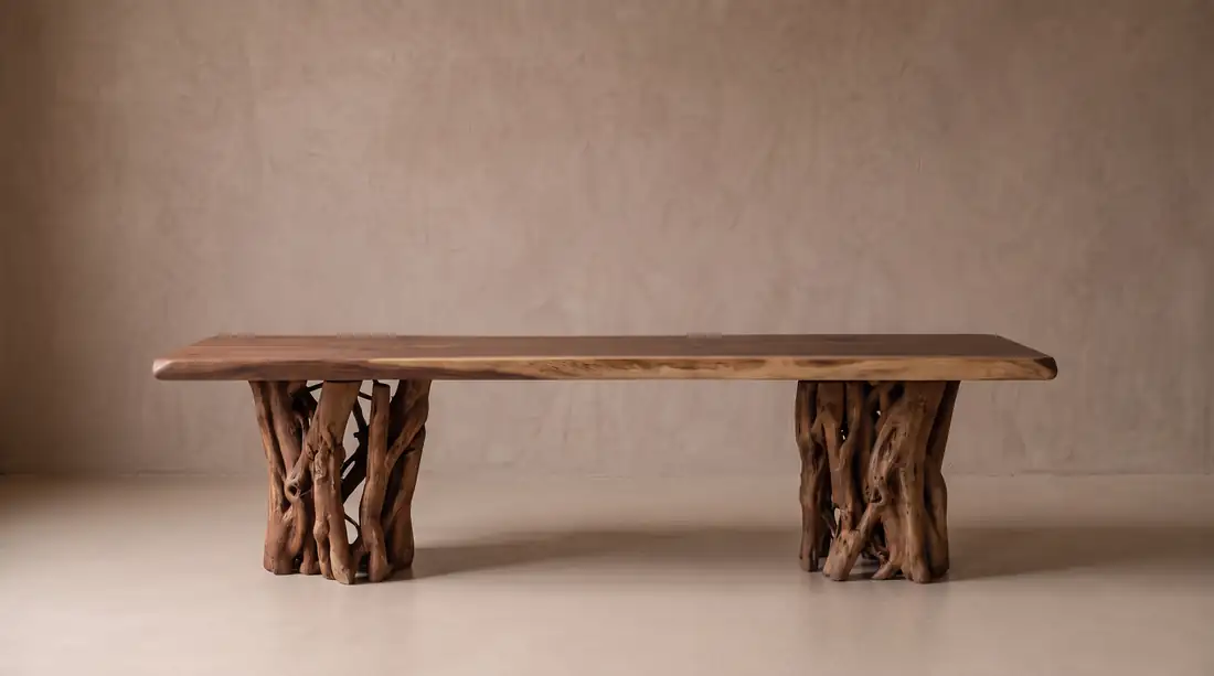 Low table with a walnut slab top resting on two tangled, weathered root bases